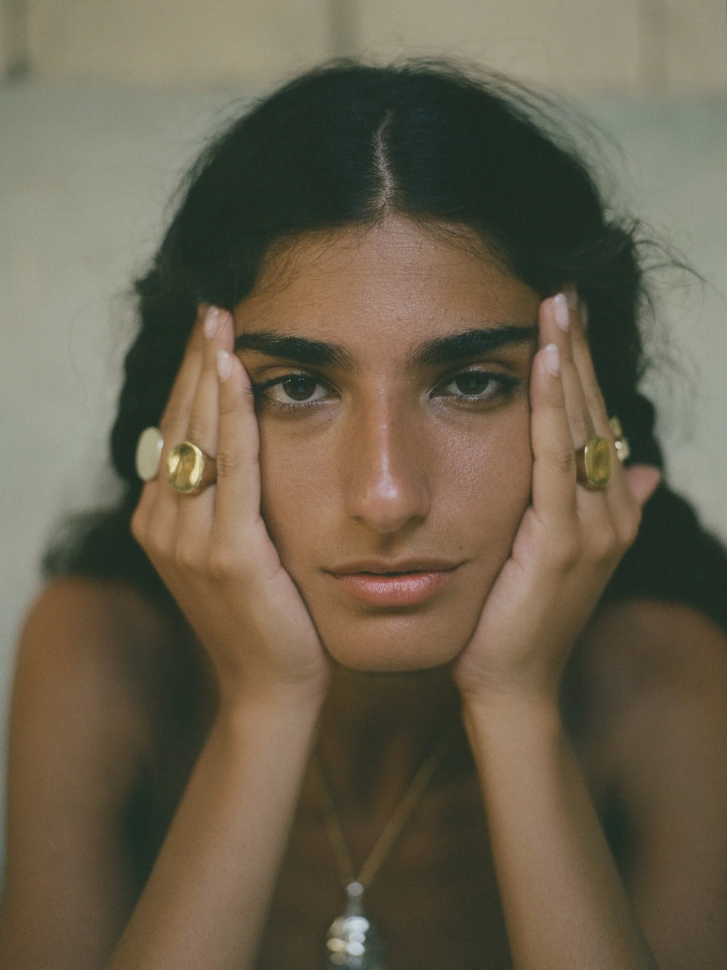 tanned woman wearing handmade, organic brass ring with 9k gold accents and textured surface