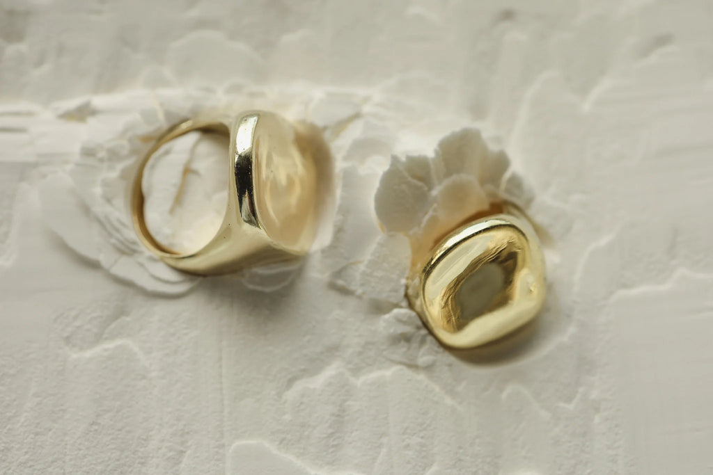 organic, feminine, brass ring with 9k gold infused and textured design, lying on white sand