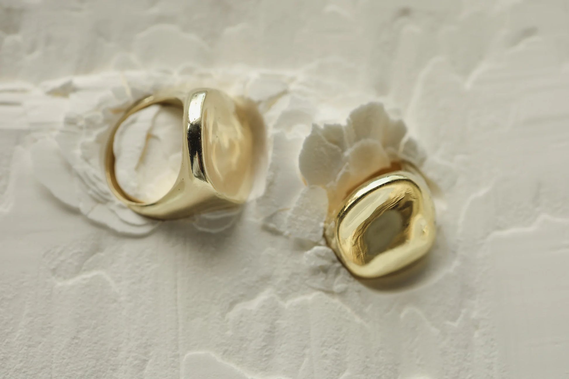 organic, feminine, brass ring with 9k gold infused and textured design, lying on white sand